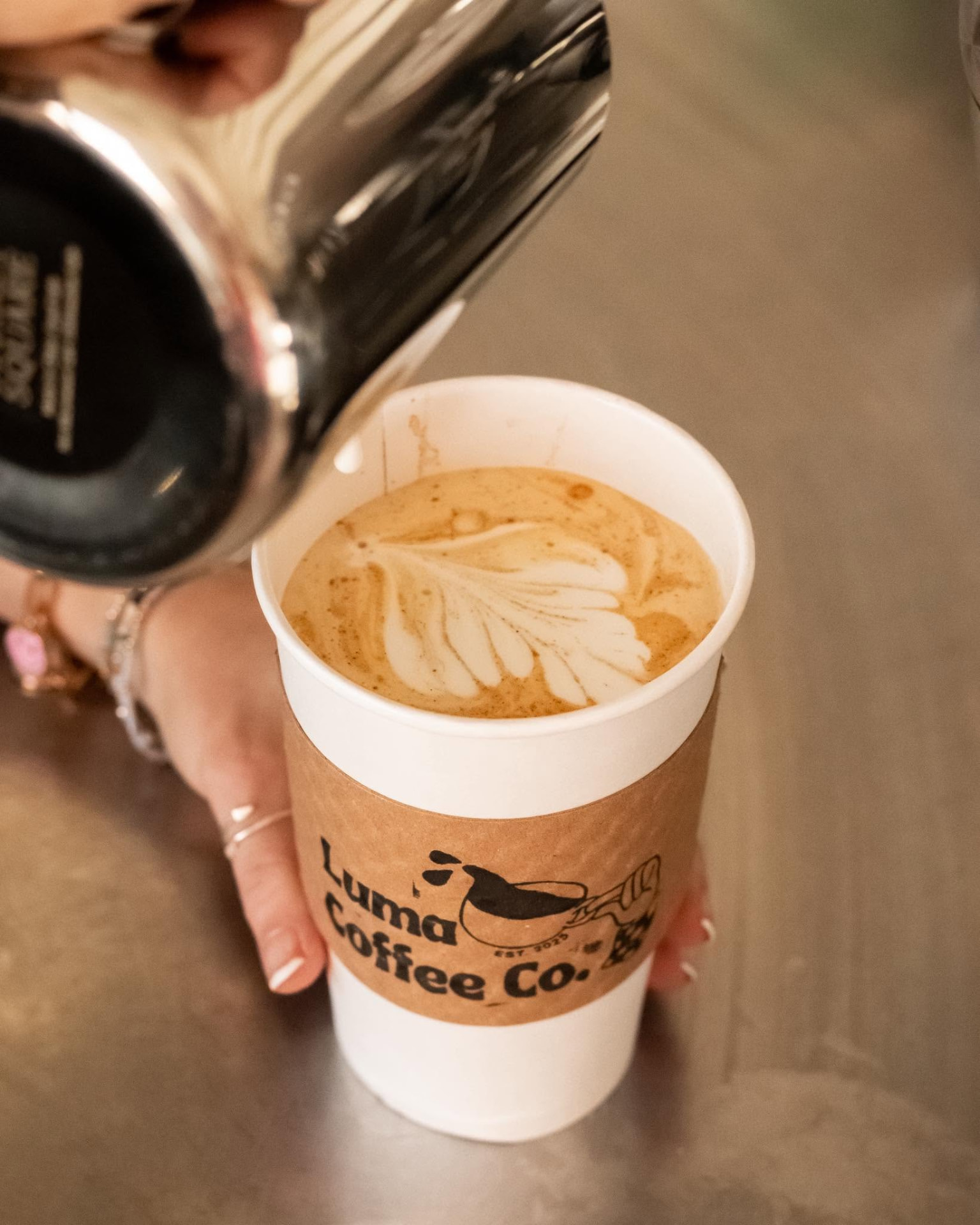 Latte art being poured into a Luma Coffee Co. cup